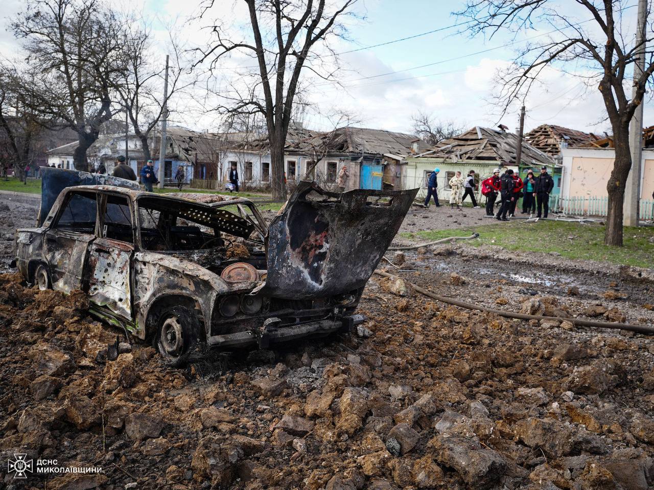 A burned out car in a dirt field

Description automatically generated