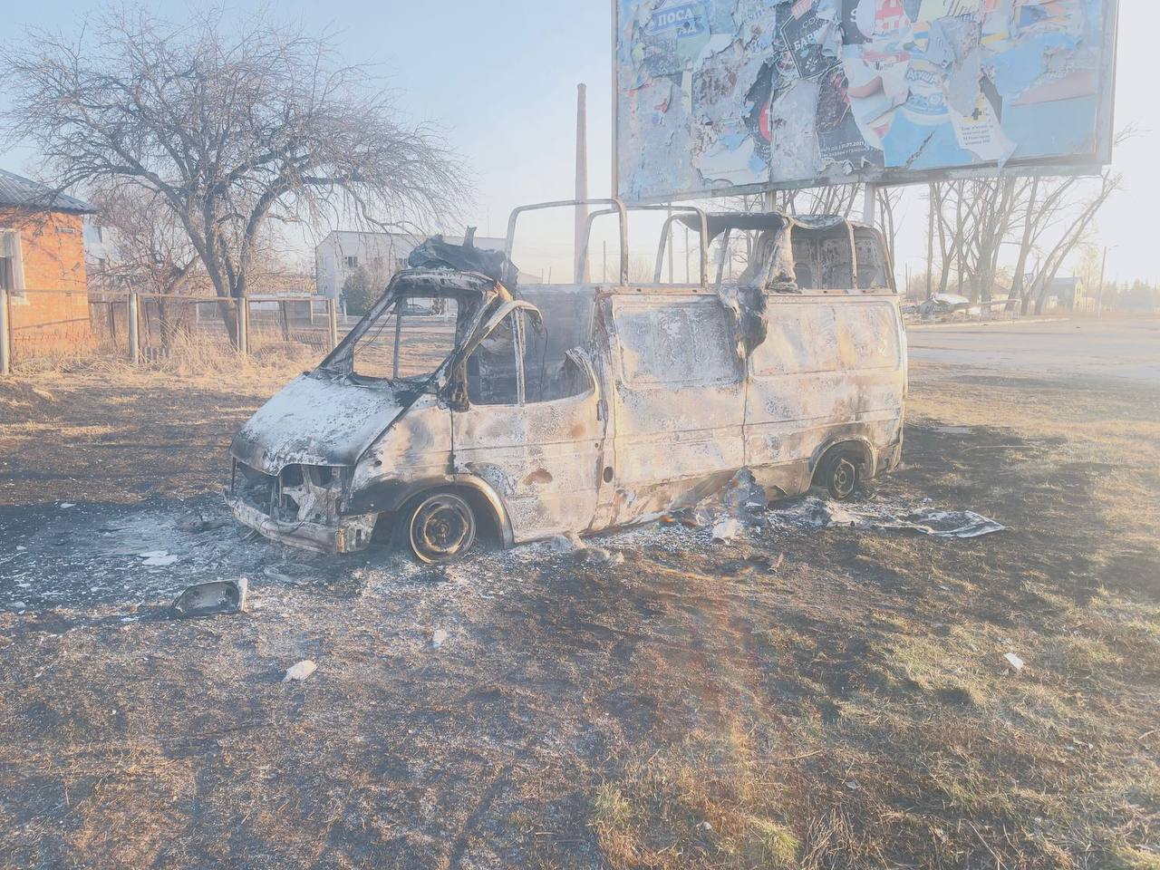 A burnt van in a field

Description automatically generated