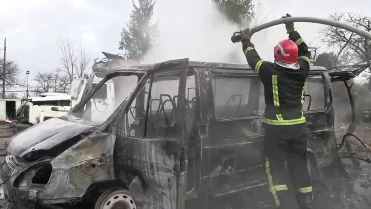 A firefighter holding a fire hose over a burnt vehicle

Description automatically generated