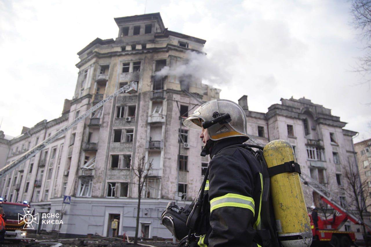 A firefighter standing in front of a building

Description automatically generated