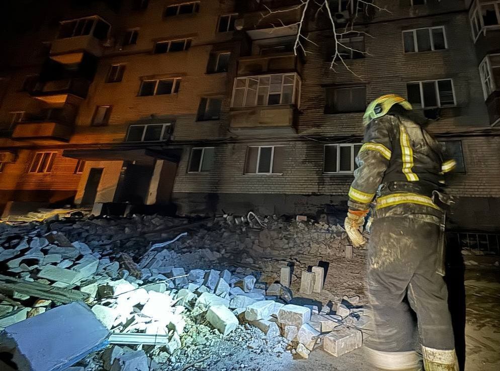 A firefighter standing in front of a building

Description automatically generated