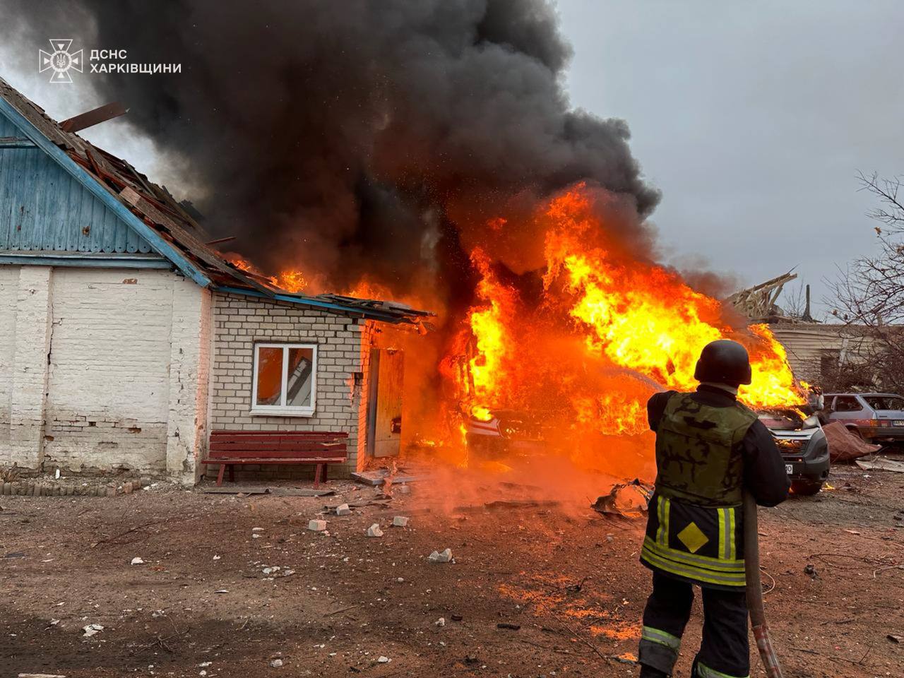 A fireman standing next to a building on fire

Description automatically generated