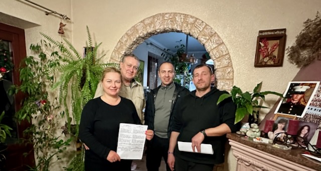 A group of people standing in front of a stone arch

Description automatically generated