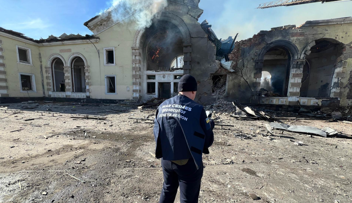 A person standing in front of a destroyed building

Description automatically generated