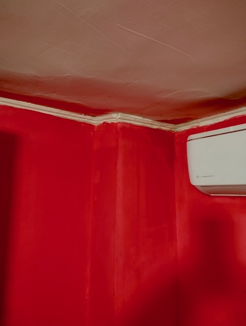 A red wall with a white air conditioner

Description automatically generated