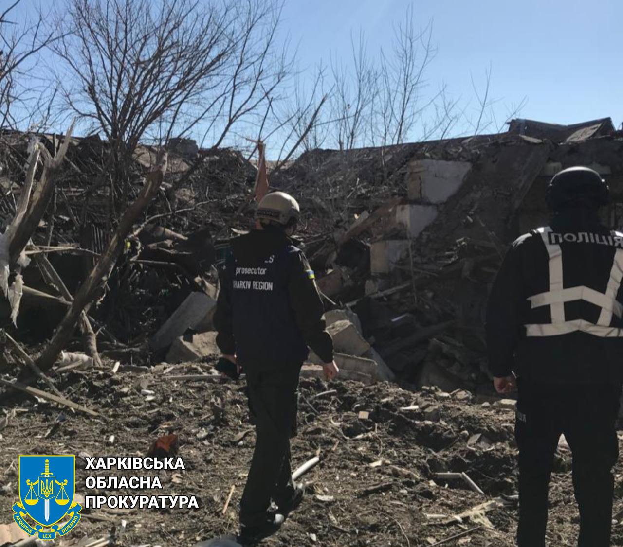 Two men in uniform standing in front of a destroyed building

Description automatically generated