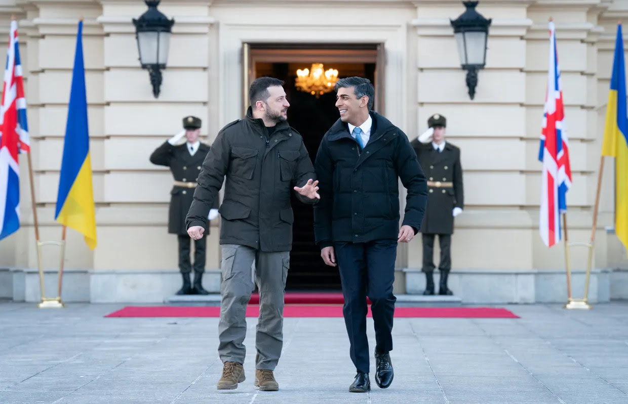 Two men walking in front of a building

Description automatically generated