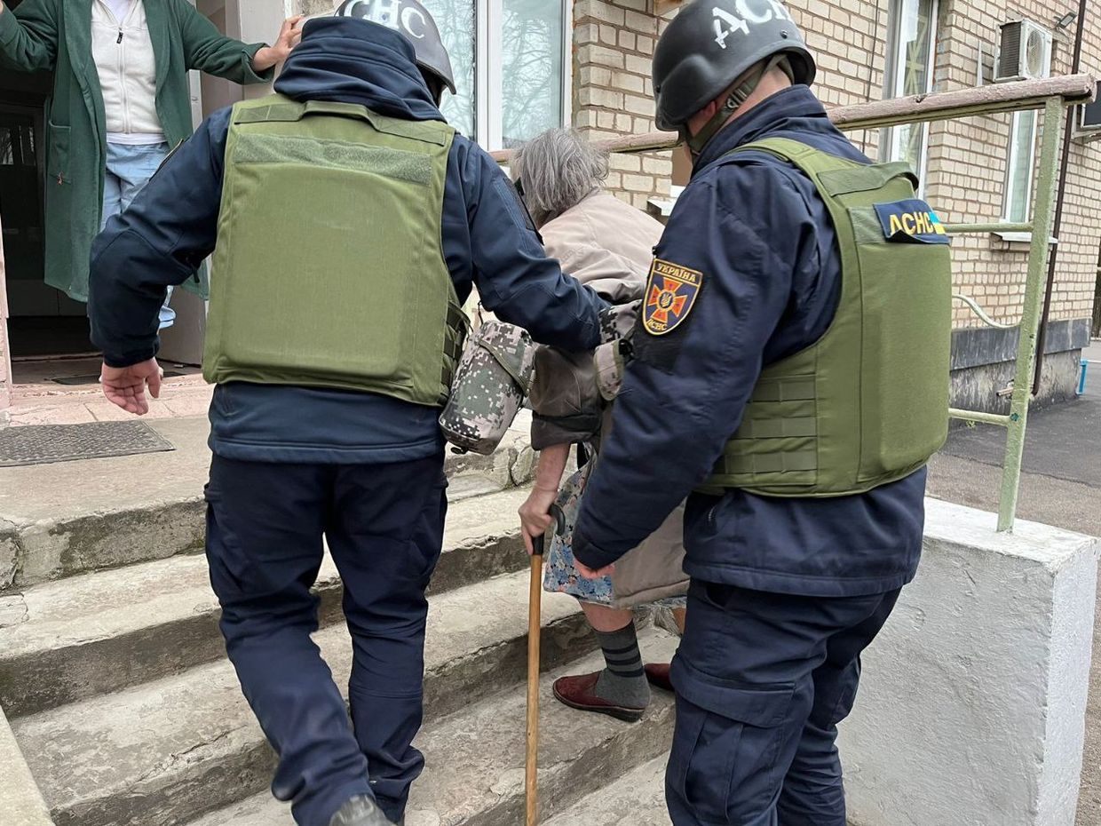 Two police officers helping an old person

Description automatically generated