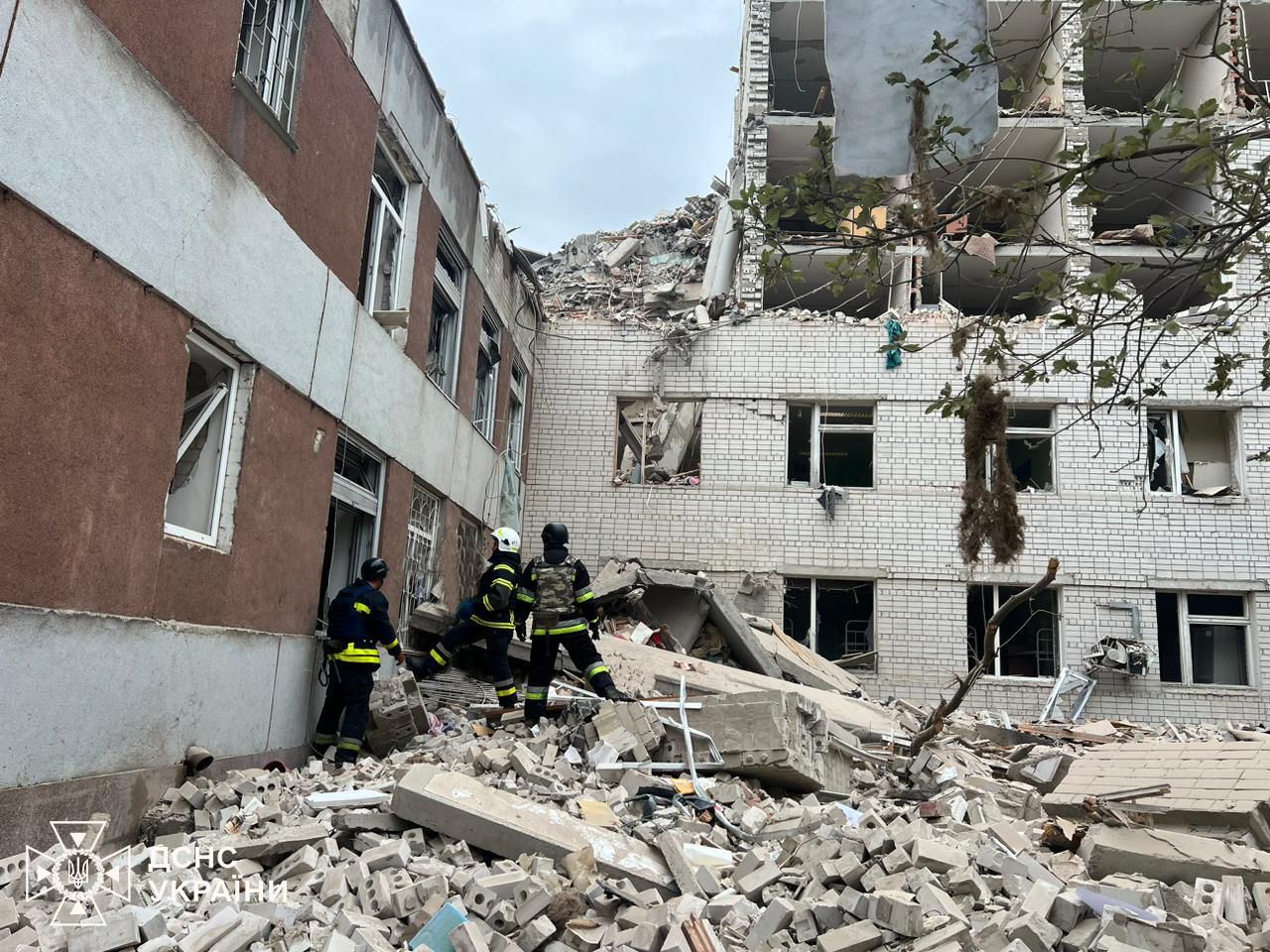 A group of firefighters standing in front of a destroyed building

Description automatically generated