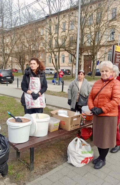 A group of women standing next to a table with buckets

Description automatically generated