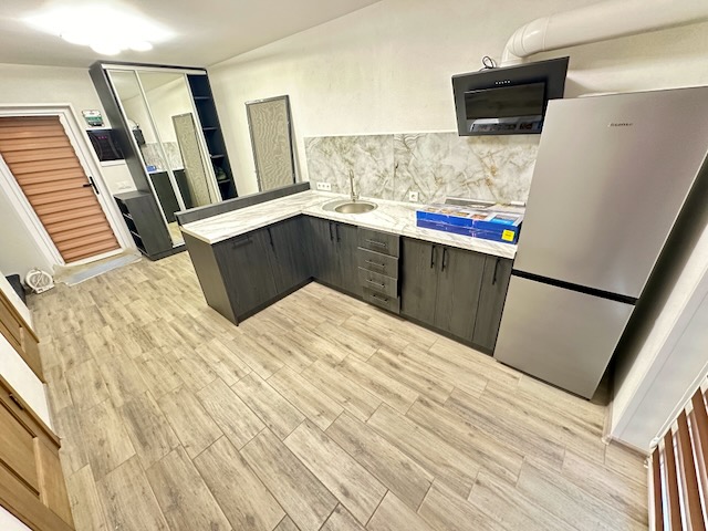 A kitchen with a wood floor

Description automatically generated