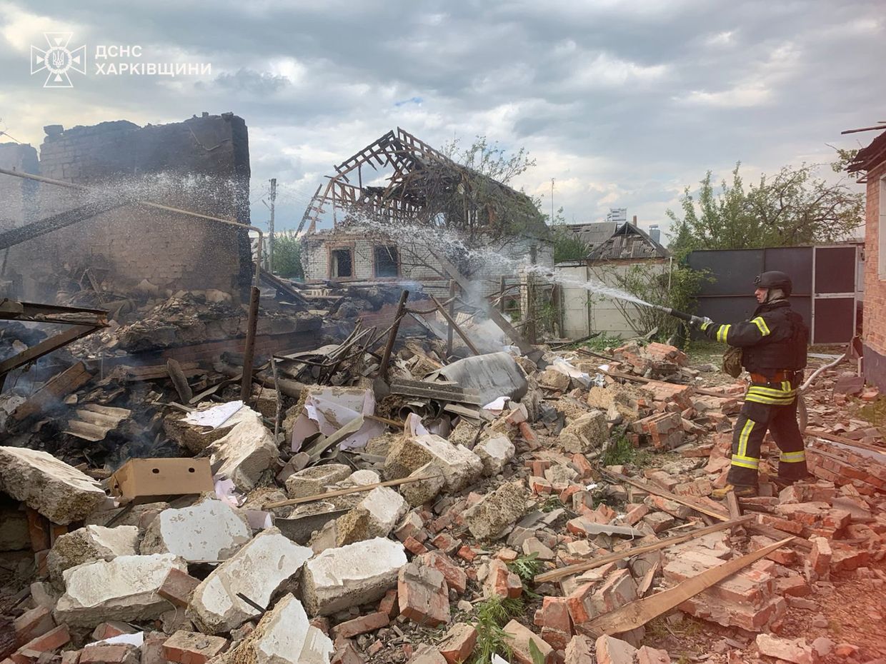 A firefighter spraying water on a destroyed building

Description automatically generated