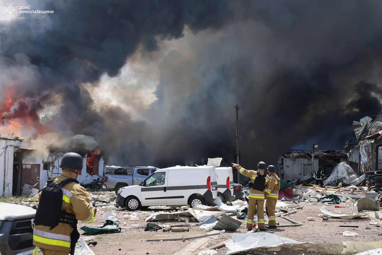 A firemen standing in front of a burning building

Description automatically generated