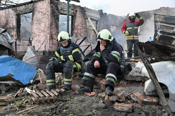 A group of firefighters sitting on rubble

Description automatically generated