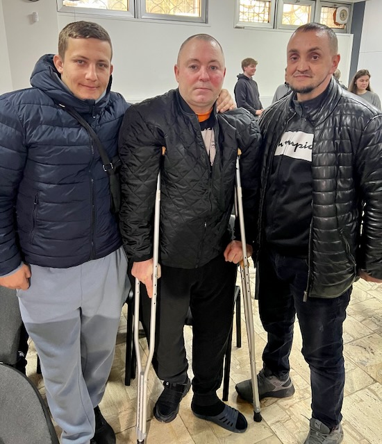 A group of men standing together with crutches

Description automatically generated