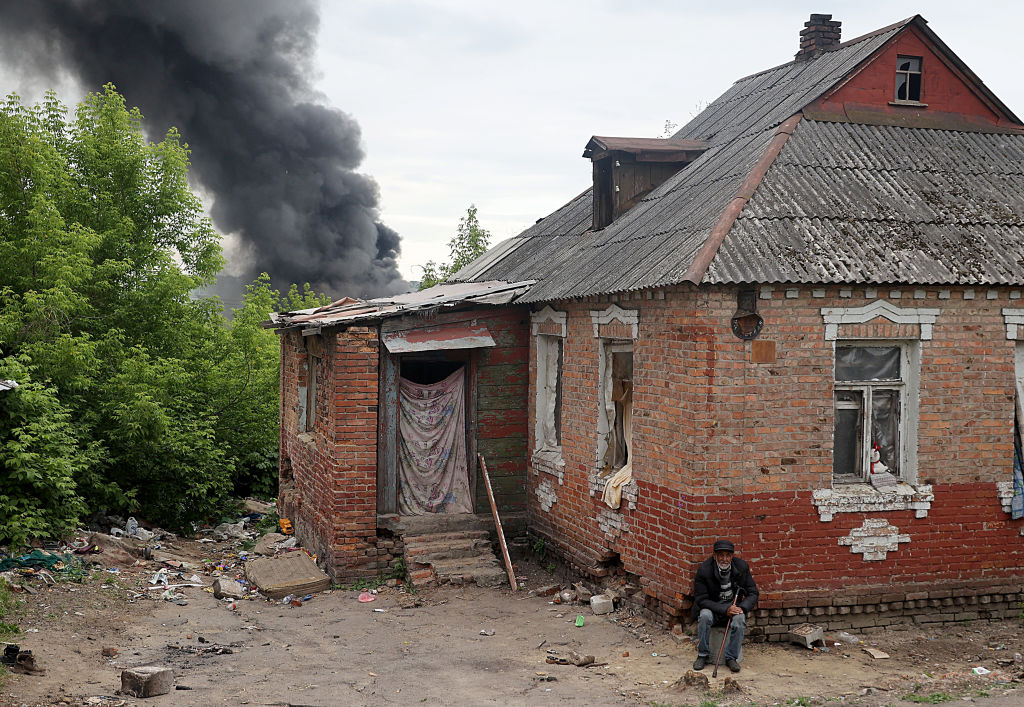 A person sitting in front of a house

Description automatically generated