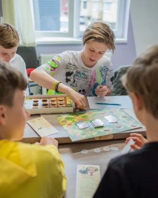 A group of people sitting around a table playing a board game

Description automatically generated