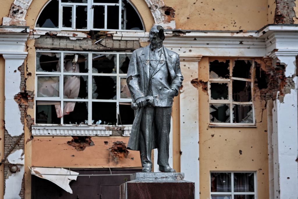 a statue of a man in front of a damaged building