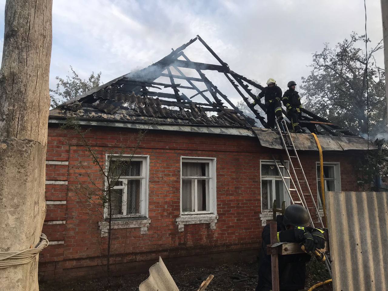 A firemen on a roof of a house

Description automatically generated