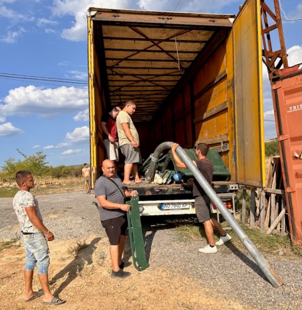 A group of men standing on a truck

Description automatically generated