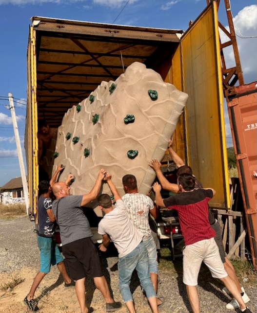 A group of people lifting a rock out of a truck

Description automatically generated