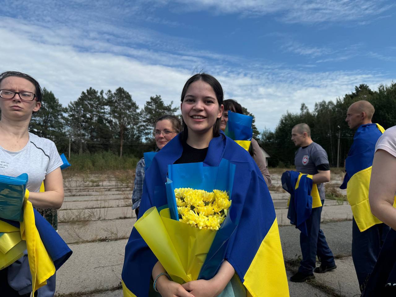 A person holding flowers and smiling

Description automatically generated