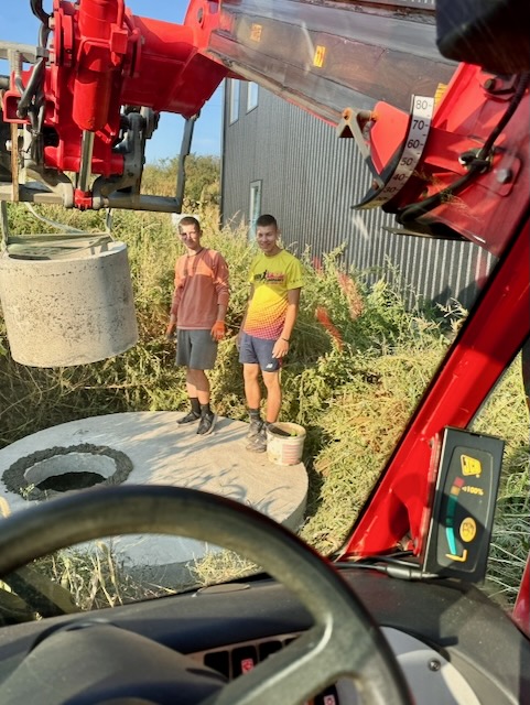 Two men standing next to a red machine

Description automatically generated