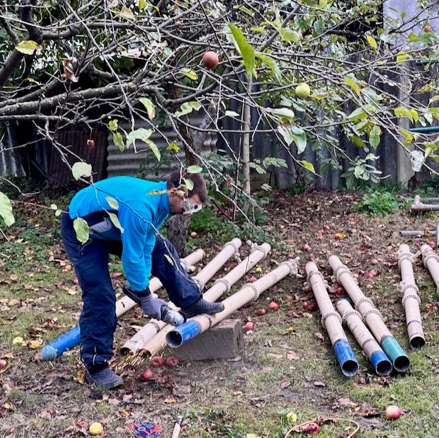 A person in blue shirt and blue pants working on a pile of pvc pipes

Description automatically generated