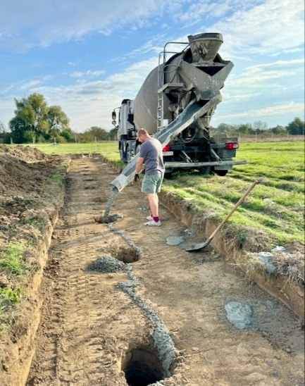 A person pouring cement into a trench

Description automatically generated