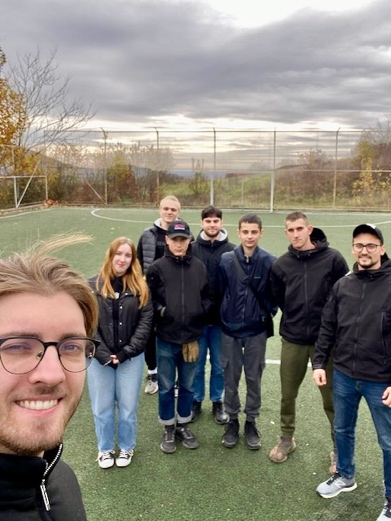 A group of people standing on a football field

Description automatically generated