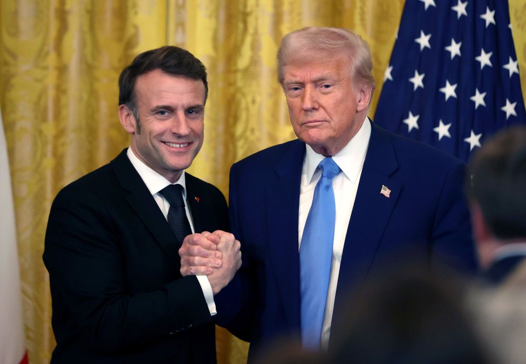 Two men shaking hands in front of a flag

AI-generated content may be incorrect.