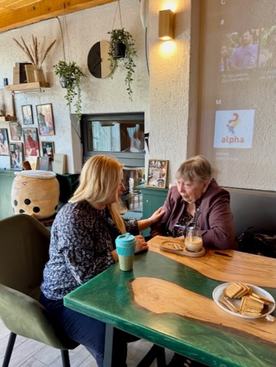 Two women sitting at a table AI-generated content may be incorrect.