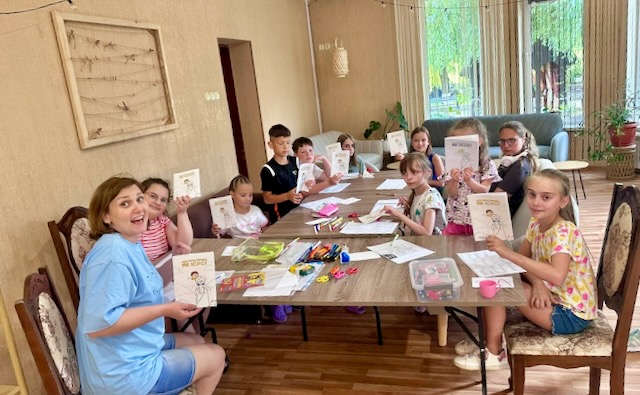 A group of children sitting at a table holding up cards AI-generated content may be incorrect.