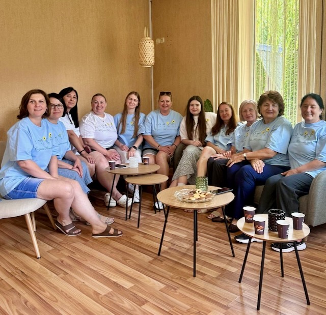 A group of women sitting in chairs and smiling AI-generated content may be incorrect.