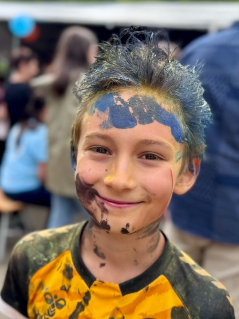 A child with blue and yellow paint on his face AI-generated content may be incorrect.