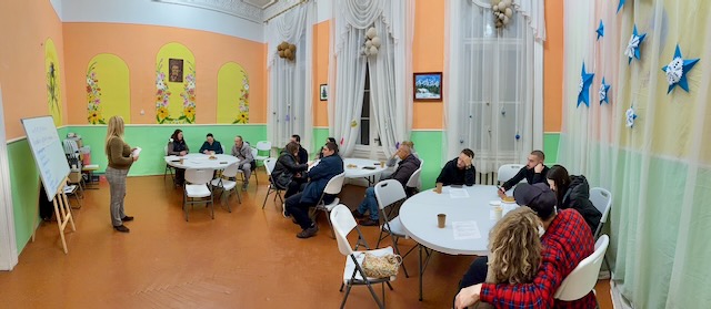 A group of people sitting at tables in a room

AI-generated content may be incorrect.