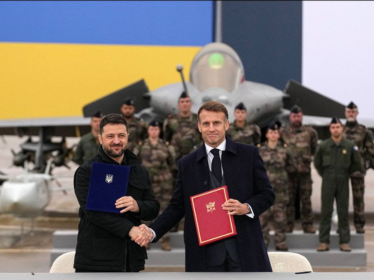 Two men shaking hands in front of military personnel

AI-generated content may be incorrect.