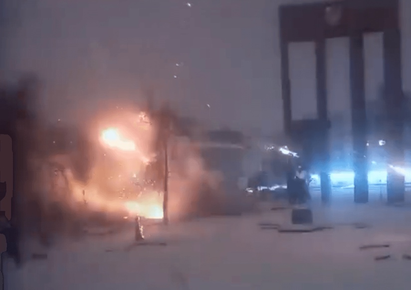 A blast erupts over a snowy city-square under a dusky sky