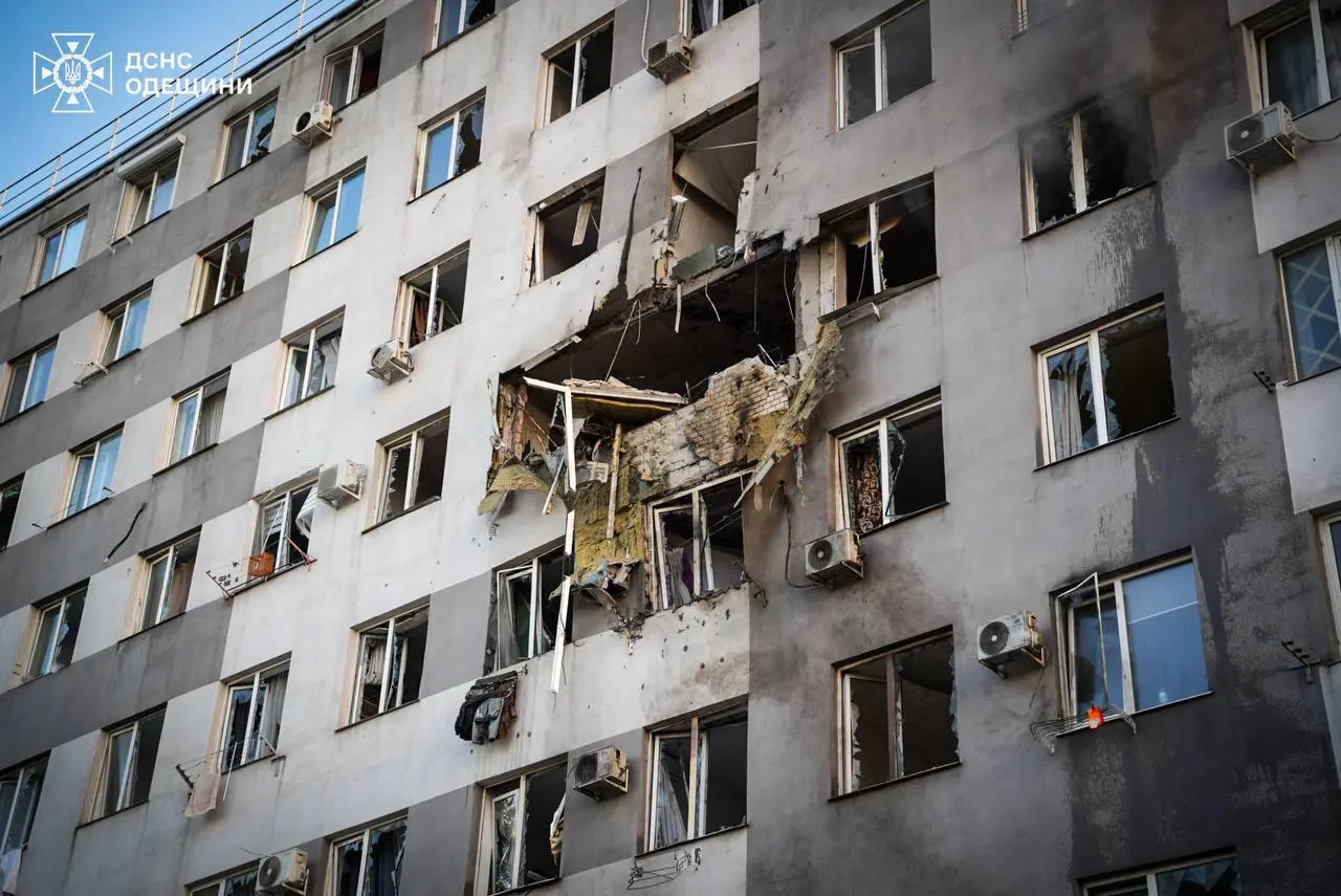 A higher floor of a residential building damaged, with windows near the site of impact shattered.