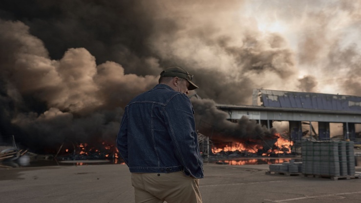 A man looks on as smoke rises from a fire at a large warehouse storing car tires and wheels following a Russian strike in Bucha district, Kyiv Oblast, Ukraine, on Aug. 29, 2026.