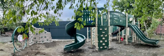 A green slide in a playground Description automatically generated